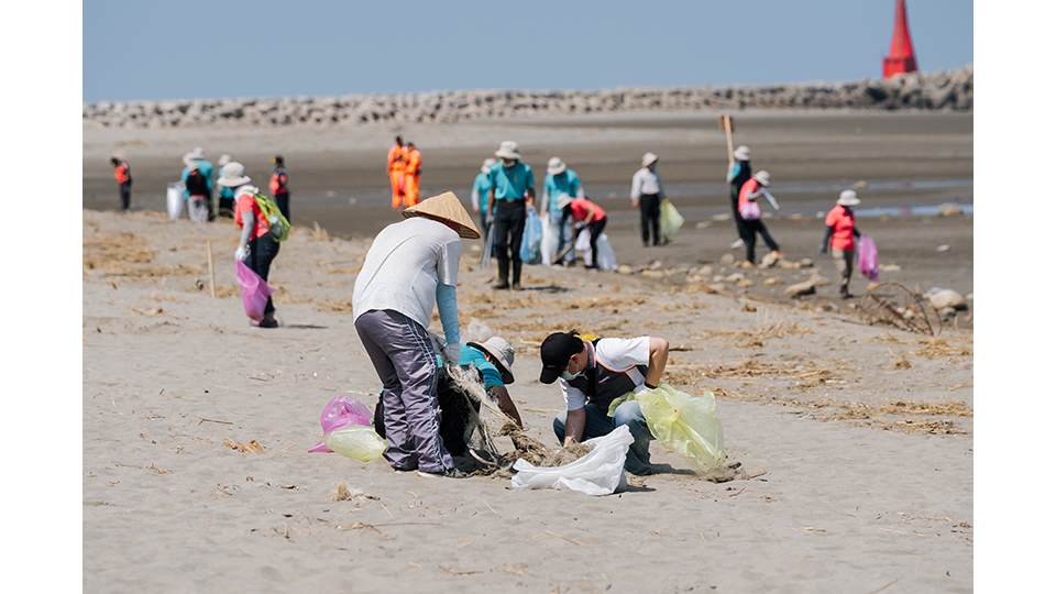即使頂著烈日，參與淨灘的民眾仍辛勤地清理沙灘上的廢棄物。